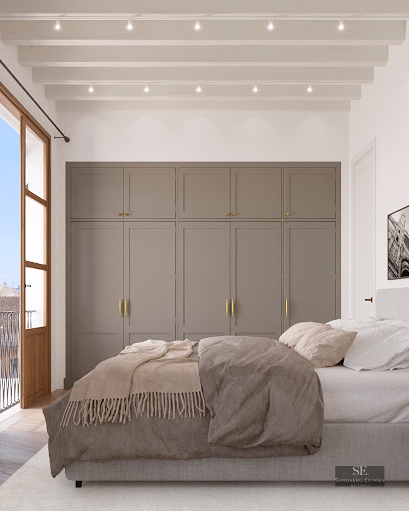 Elegant bedroom featuring wooden French doors, beige built-in wardrobes, and a white beamed ceiling.