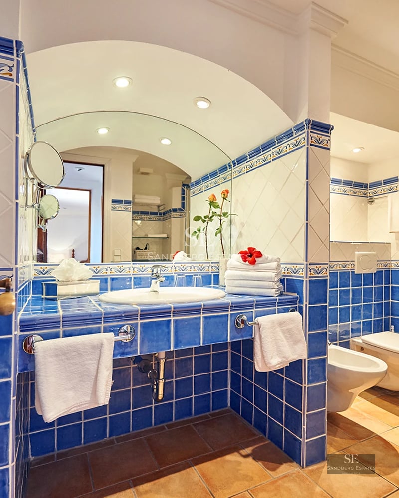 View of modern living room with fireplace, gray sofas, light rug, and large windows illuminating the space. Elegant and minimalist design.