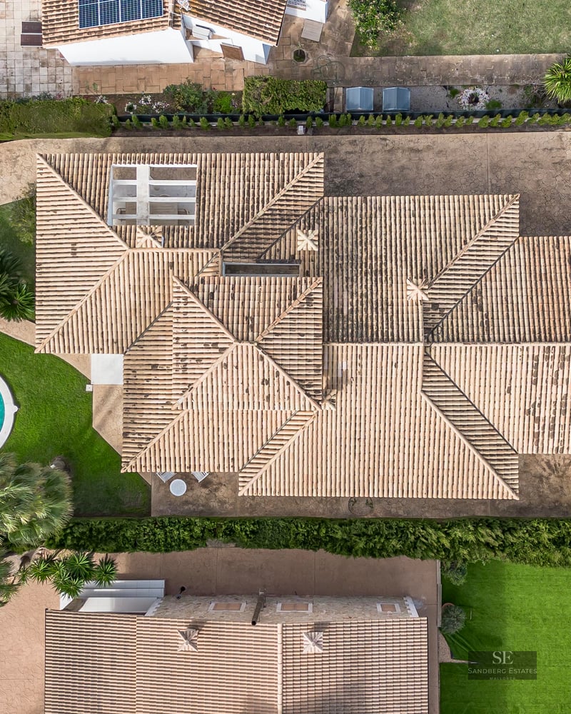 Top-down aerial view of a large villa featuring a terracotta tiled roof, private swimming pool, and landscaping.