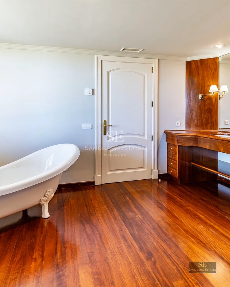 Spacious living room with windows, designer sofas, and balcony access with view. Natural lighting and wood floors.