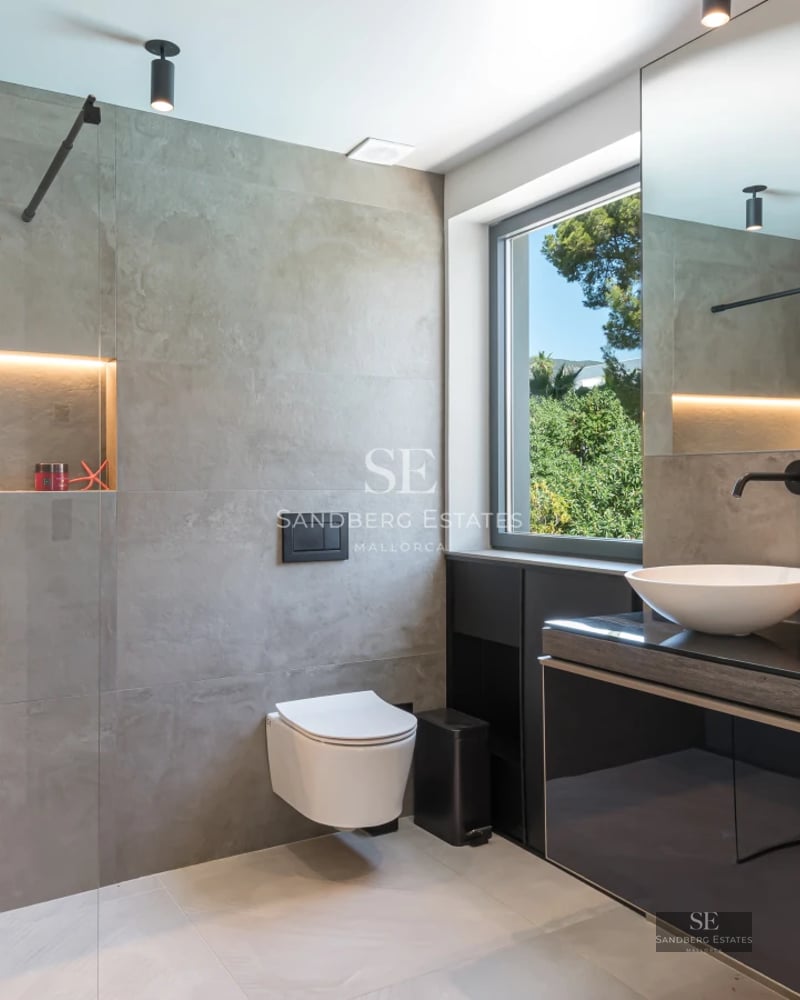 Exterior view of a modern villa featuring a swimming pool, lush gardens, and large windows reflecting sunlight.