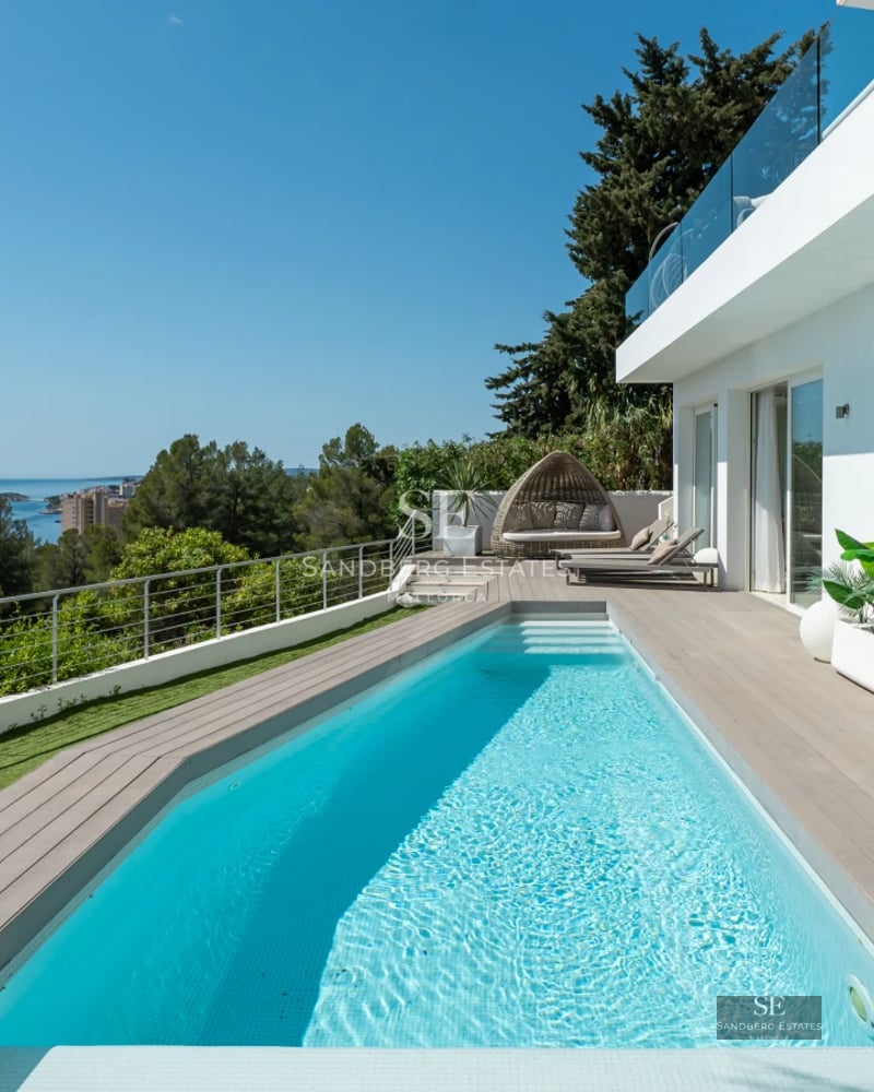 Exterior view of a modern home with pool, large windows, and lush garden. Minimalist architecture and high-quality finishes.