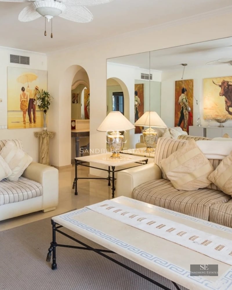 Spacious, bright living room with large windows, light wood flooring and modern furniture. Panoramic outdoor views.