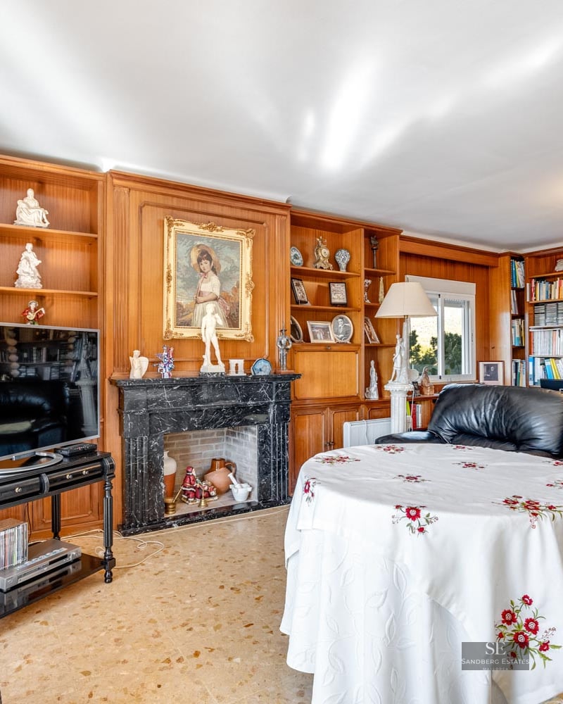 Traditional living room featuring a black marble fireplace, custom wood shelving, and black leather sofas.