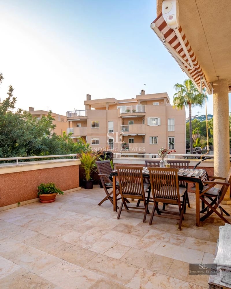 Grand balcon avec vue panoramique sur la mer. Garde-corps en verre, sol en bois et mobilier moderne. Lumineux et spacieux.