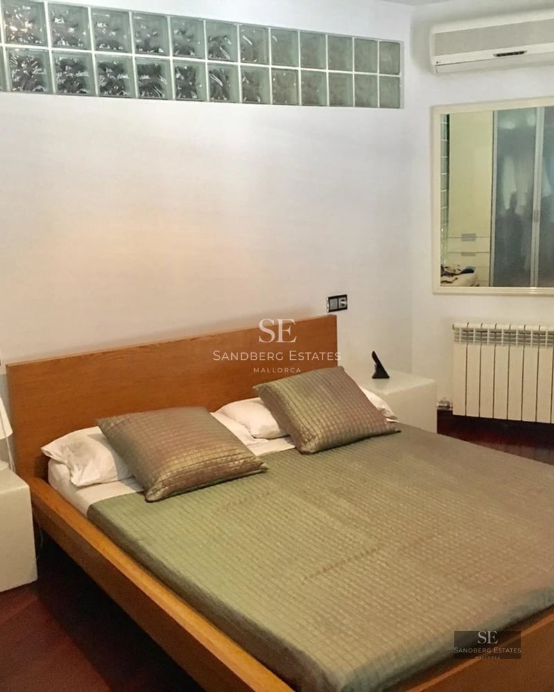 Spacious living room with picture windows, light wood floors, and minimalist design. Abundant natural light. Gray modular sofa.