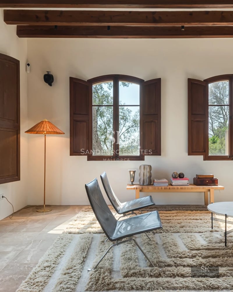 Bright living room featuring floor-to-ceiling windows overlooking a reflective pool. Modern interior with designer furniture and neutral color palette.
