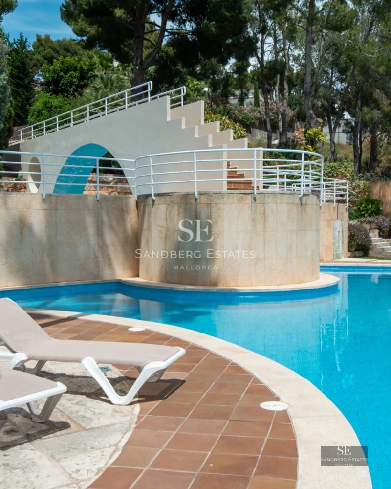 Exterior view of a modern villa featuring an infinity pool, expansive terraces, and lush garden. Minimalist architecture with large windows.