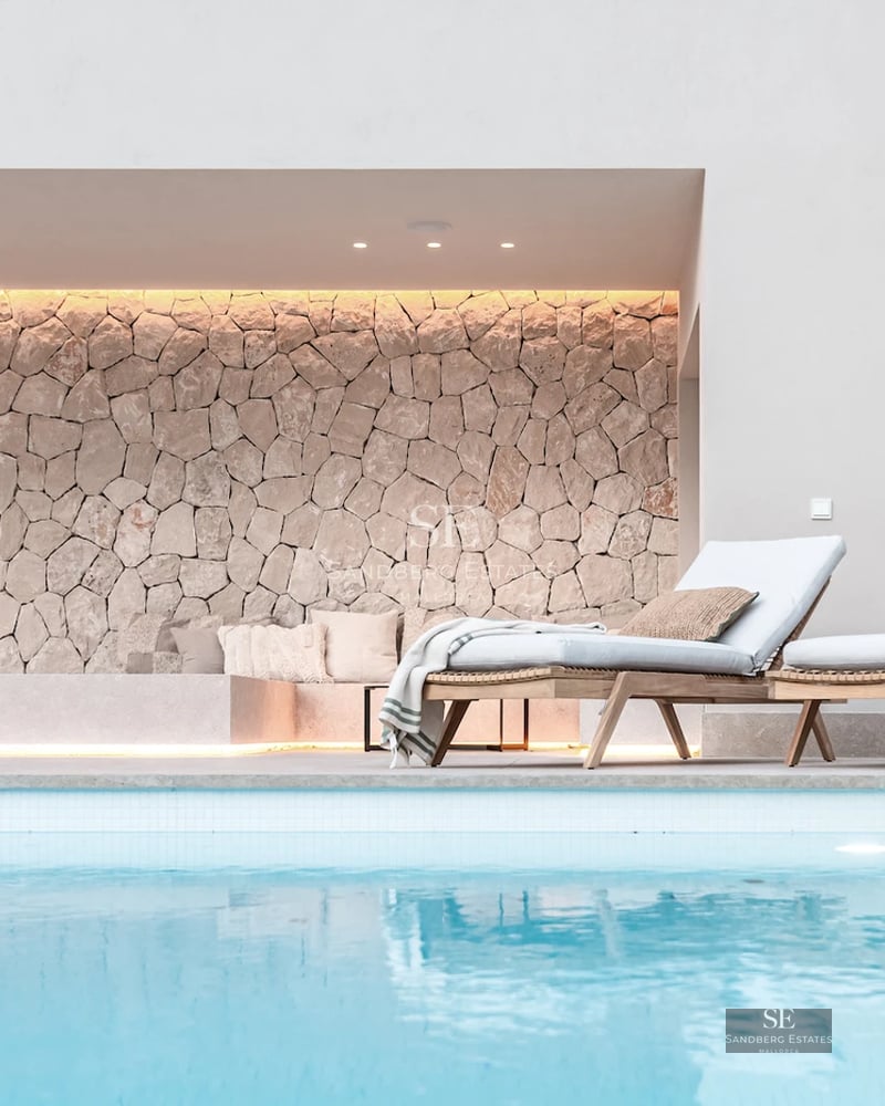 Spacious balcony with glass railing, wooden floor, panoramic view of the city skyline and blue sky at sunset.