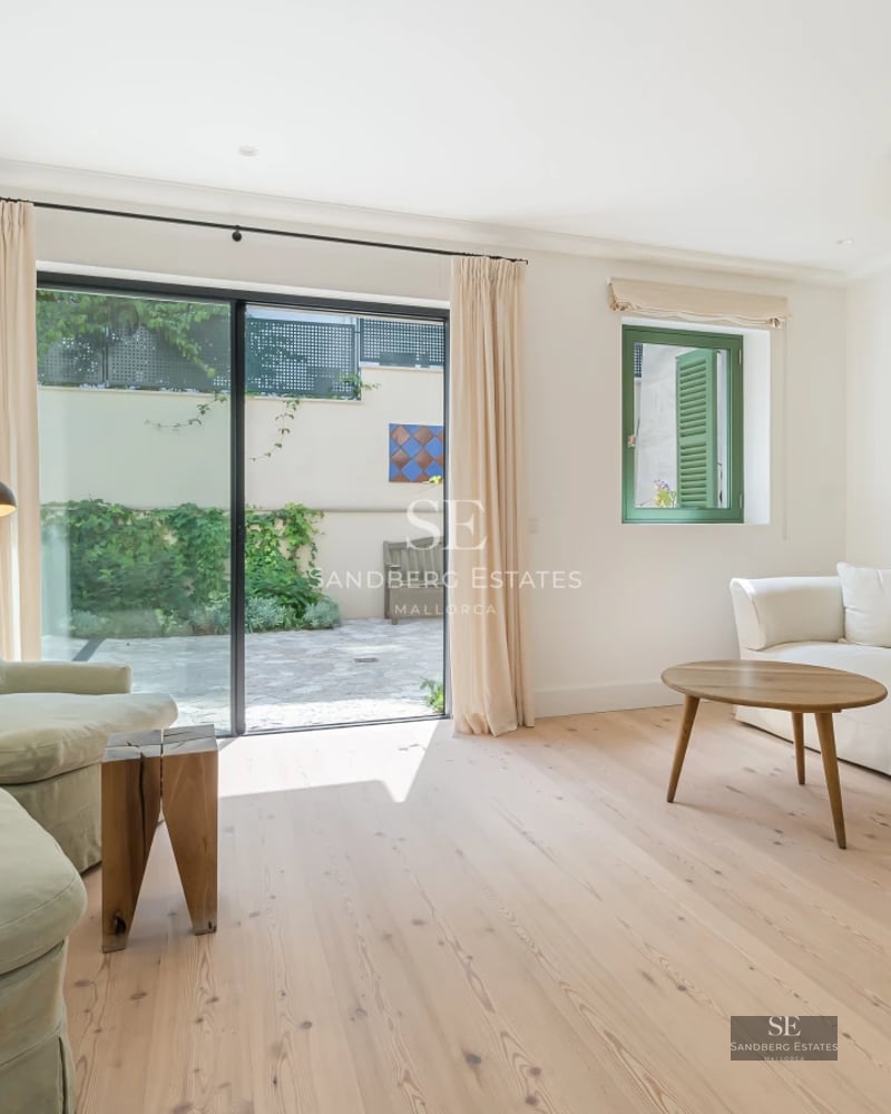 Spacious balcony with glass railings, panoramic sea views, and modern furniture. Wooden flooring and vegetation.