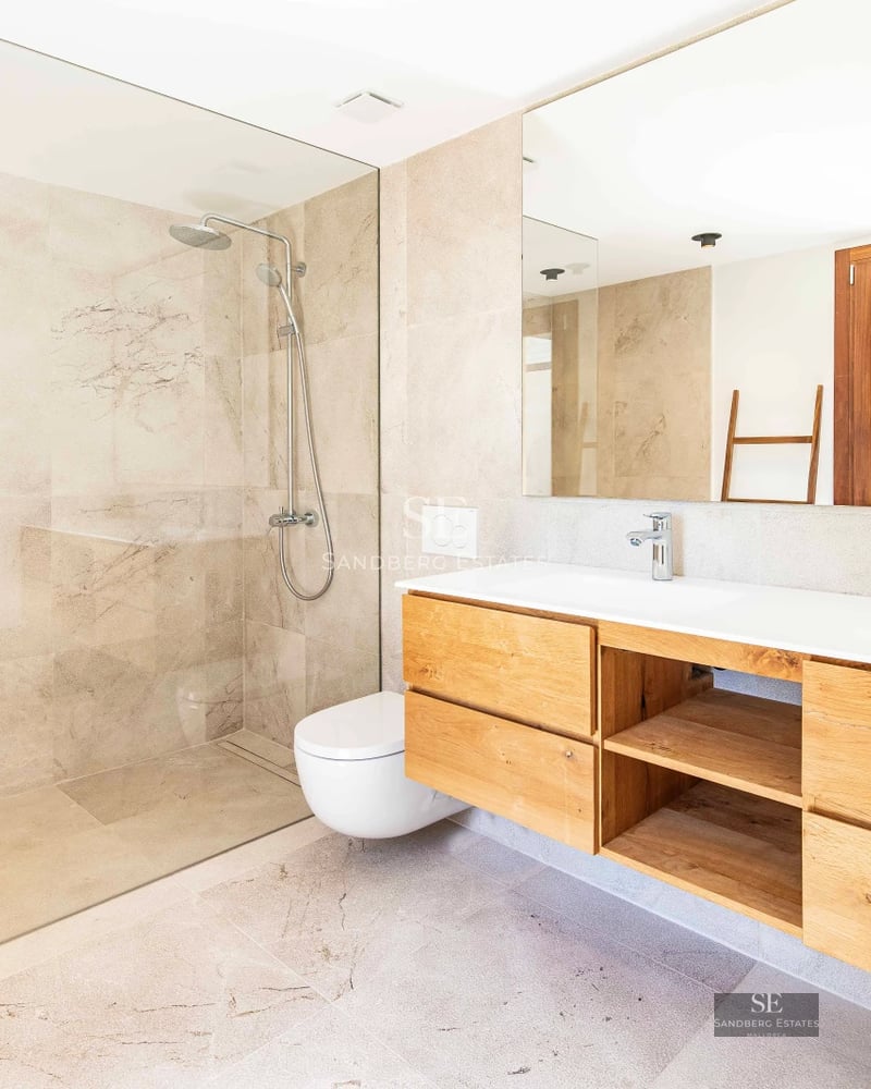 Spacious terrace with an infinity pool and panoramic sea views. Modern and elegant furniture, wooden floors, and glass railing.