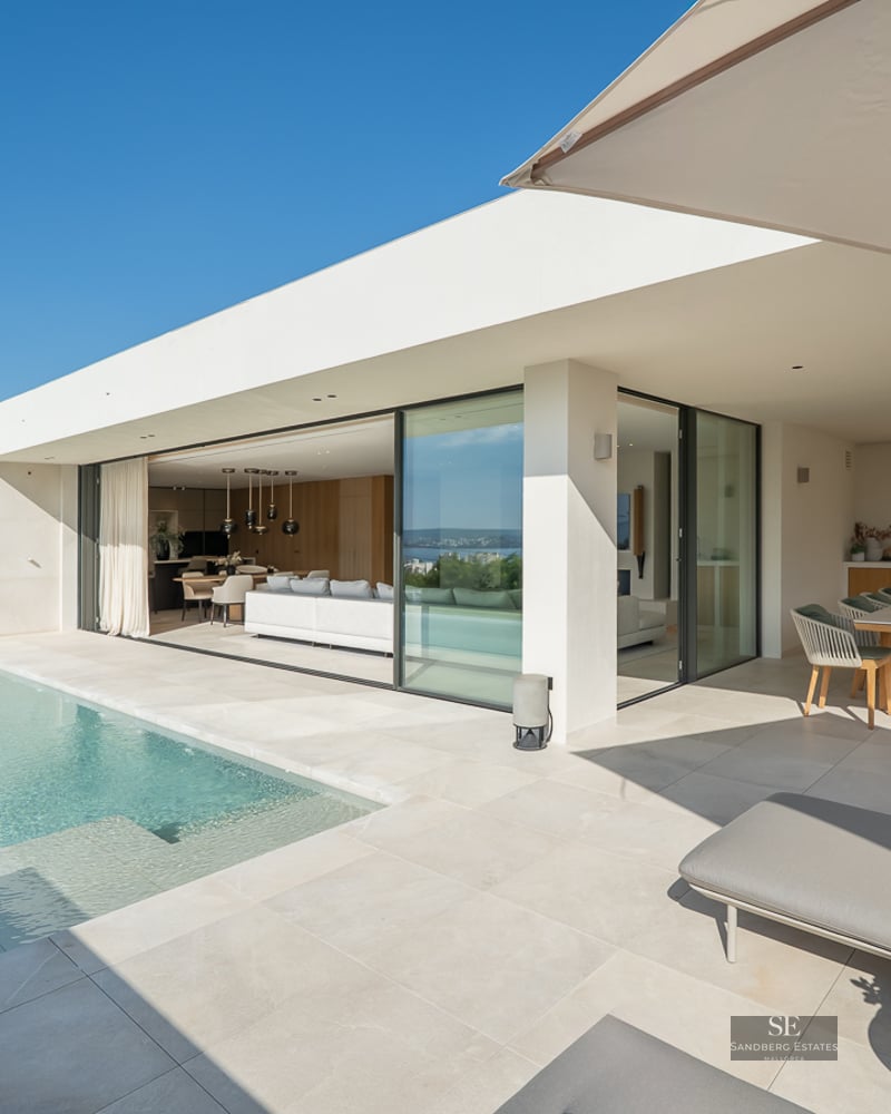 Modern villa terrace with infinity pool, sun loungers, outdoor dining area, and seamless indoor-outdoor living space.