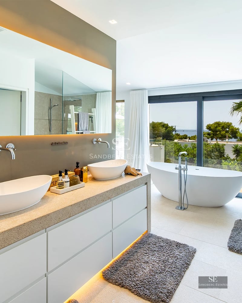 Exterior view of a modern villa featuring a reflecting pool, large windows, and minimalist design in neutral tones.