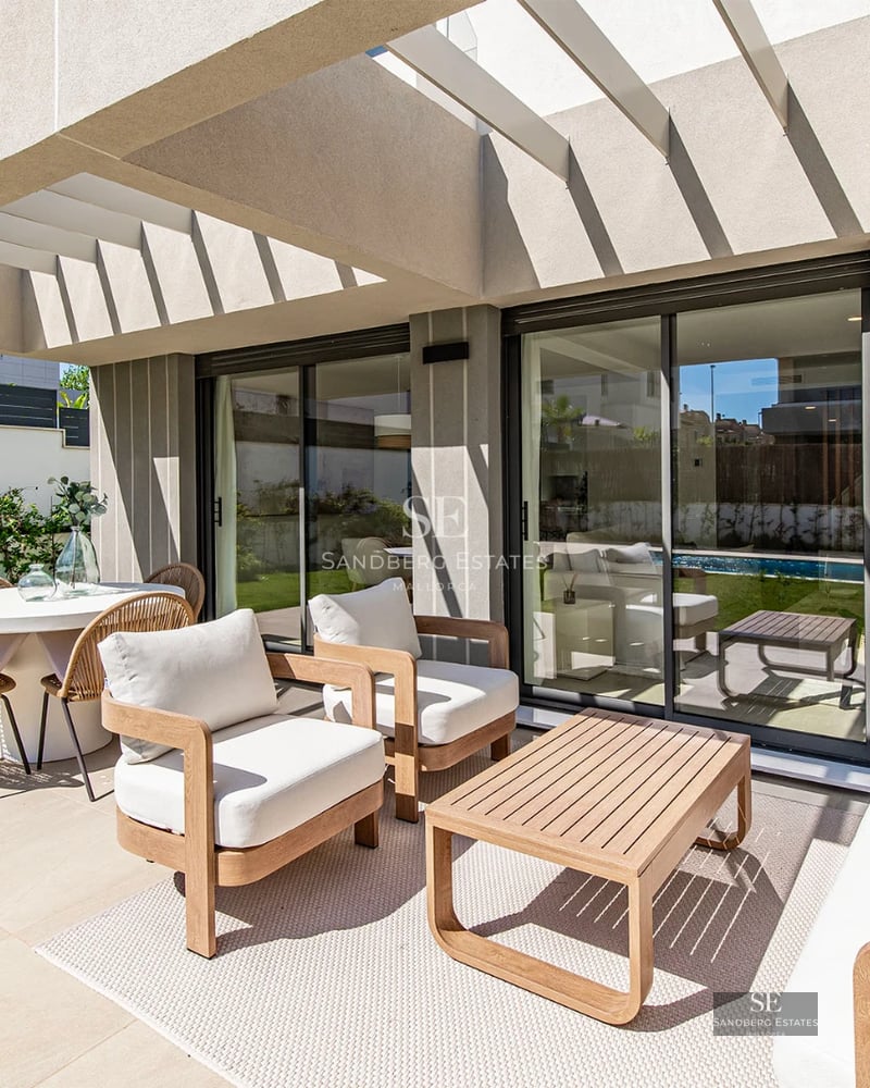 View of modern villa with infinity pool, lush garden, and minimalist architectural design. Large windows and covered terrace.