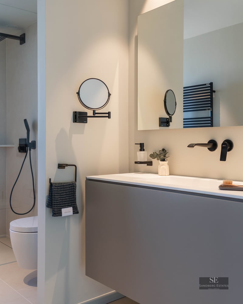 Modern bathroom featuring a grey floating vanity, matte black fixtures, and a large rectangular mirror.