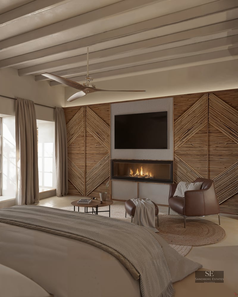 Spacious bedroom with a modern fireplace, leather armchair, wooden beamed ceiling, and a large bed in the foreground.