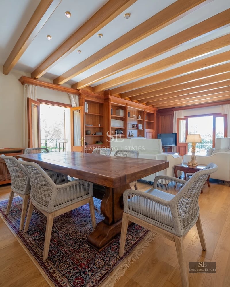 View of infinity pool surrounded by lush greenery and modern architecture with large windows.