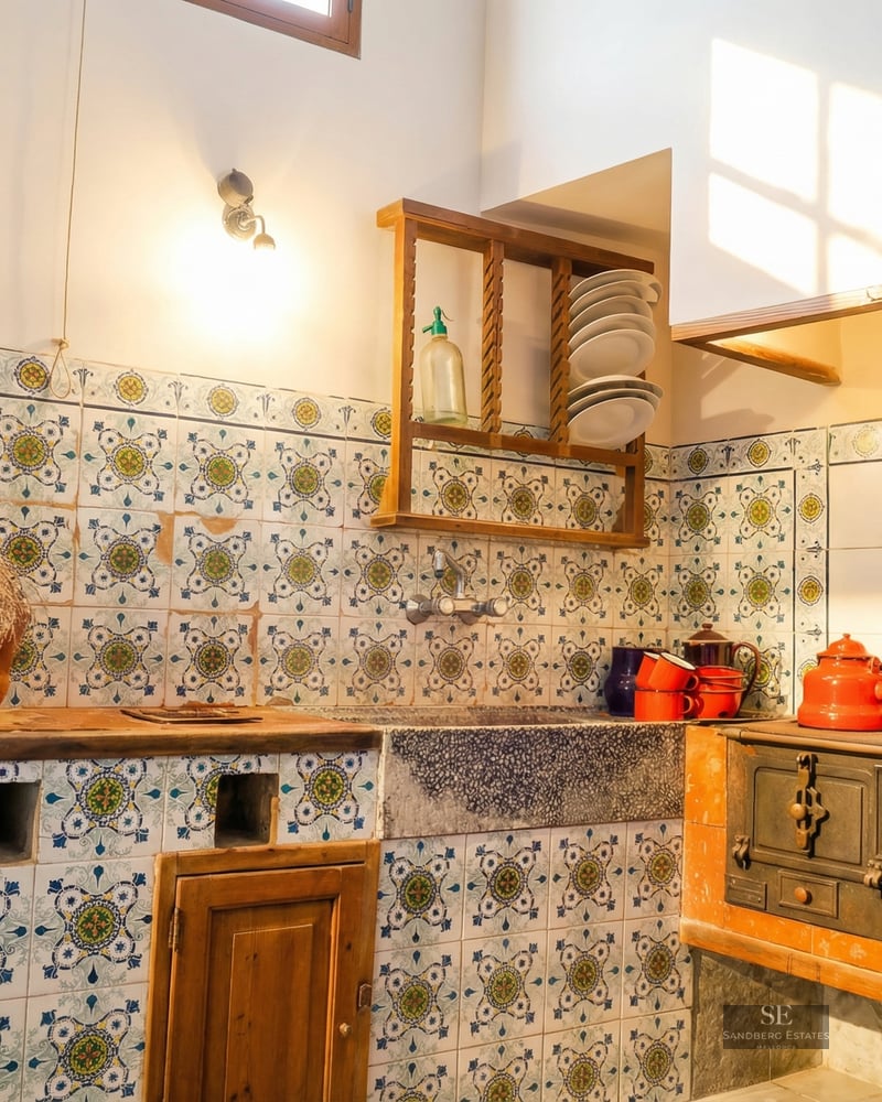 Rustic kitchen featuring hand-painted patterned tiles, a stone sink, and a vintage cast iron wood-burning stove.