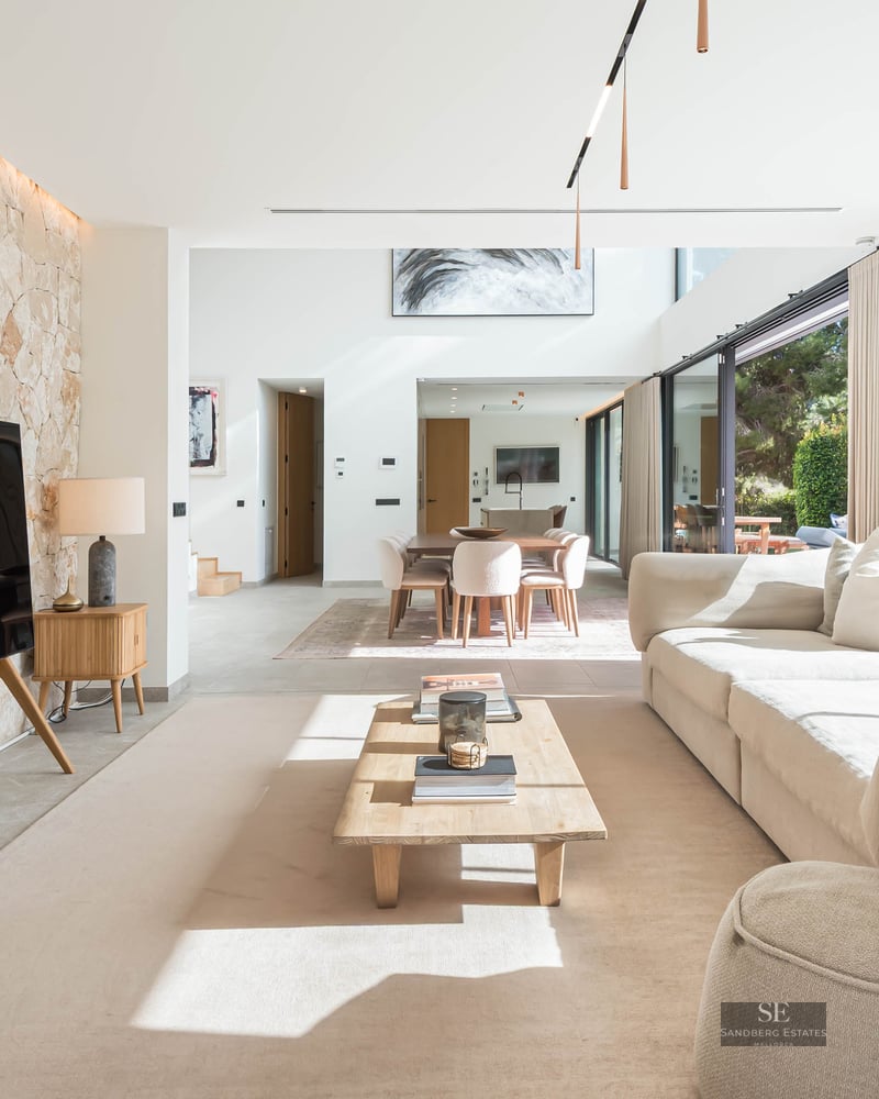 Salon spacieux avec un grand canapé crème, une table basse en bois et un mur d'accent en pierre naturelle claire.