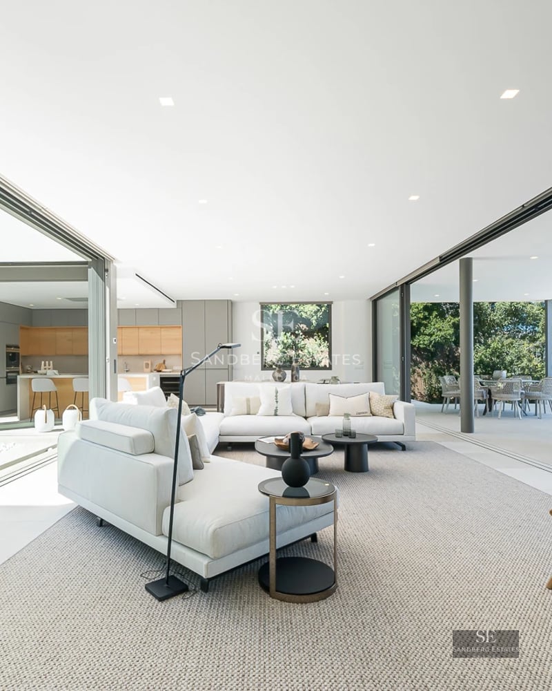 Large infinity pool, surrounded by lush vegetation and a modern house with large windows. Panoramic view of the horizon.