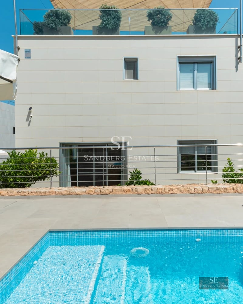 Exterior view of a luxury residence featuring an infinity pool, expansive windows, and modern landscaping.