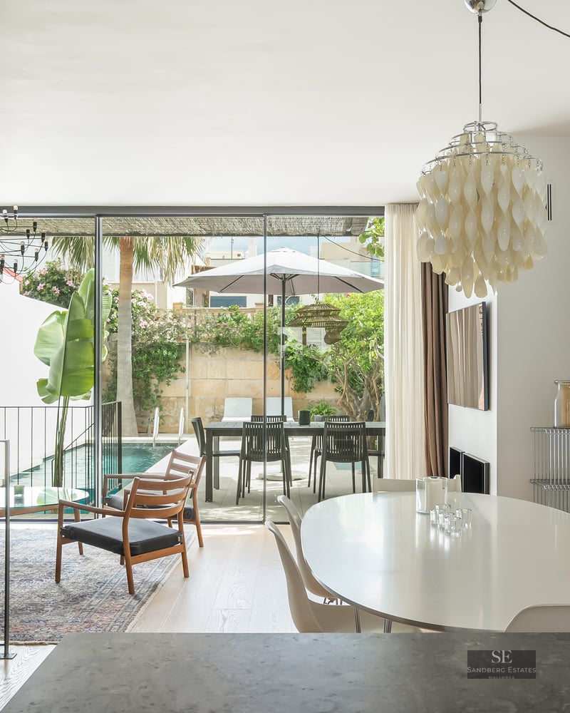 Bright open-plan living and dining room with floor-to-ceiling glass doors opening to a private pool and terrace.
