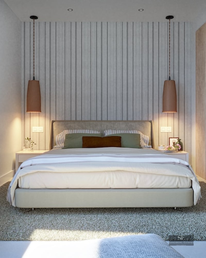 Modern bedroom featuring a large bed, wood paneling, designer pendant lights, and a plush grey rug.