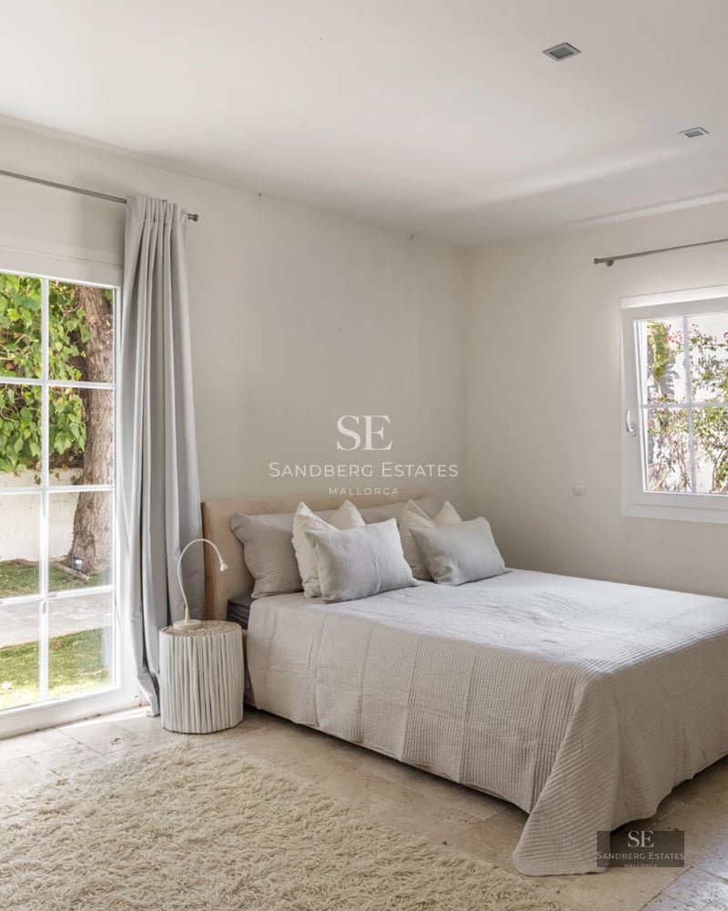 Spacious living room with floor-to-ceiling windows, light wood flooring, modern fireplace and minimalist furniture. Panoramic sea views. Bright and elegant.