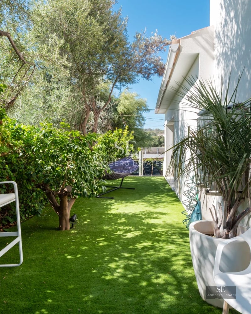 Bright living room with large windows, modern furniture, wooden floor, and a stunning panoramic sea view.