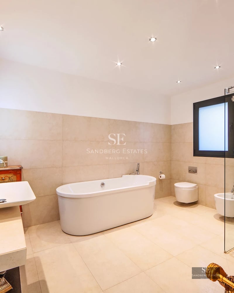 Spacious living room with large windows, sea view, light wood floors and modern, elegant furniture.