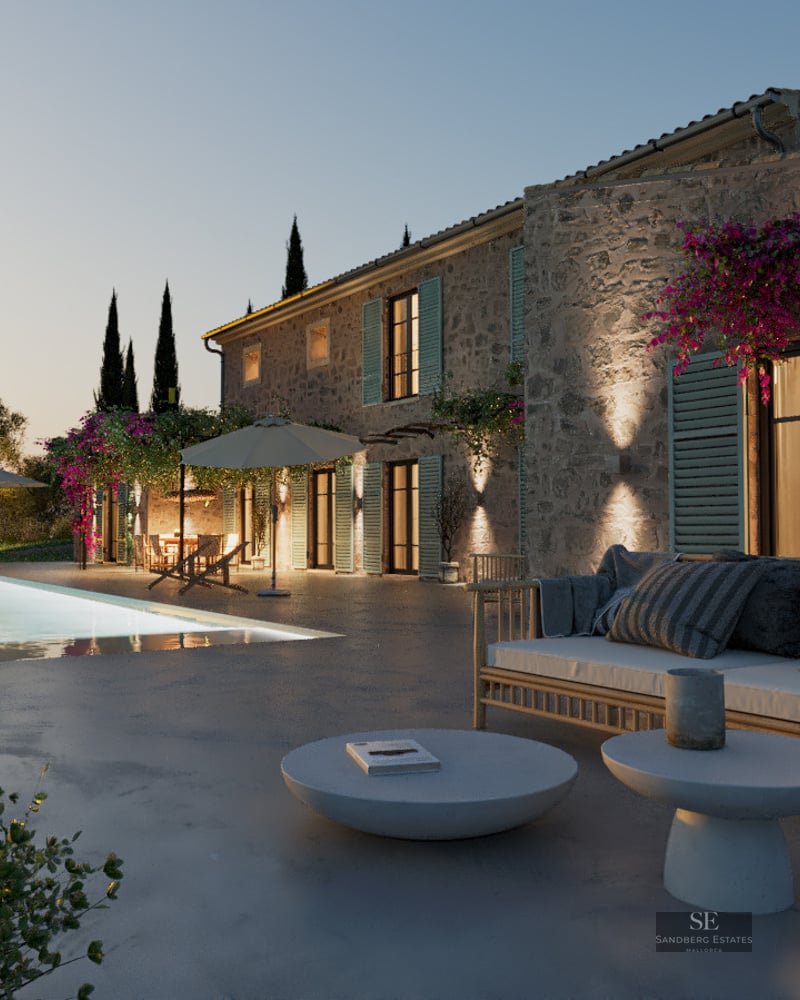 Stone villa at dusk featuring a glowing swimming pool, modern terrace furniture, and cypress trees under a twilight sky.