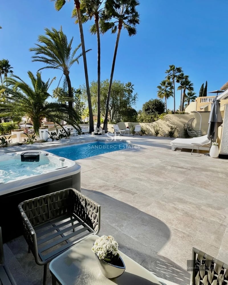 Aerial view of a luxurious villa with infinity pool, wooden terrace, and lush garden. Modern and minimalist design.