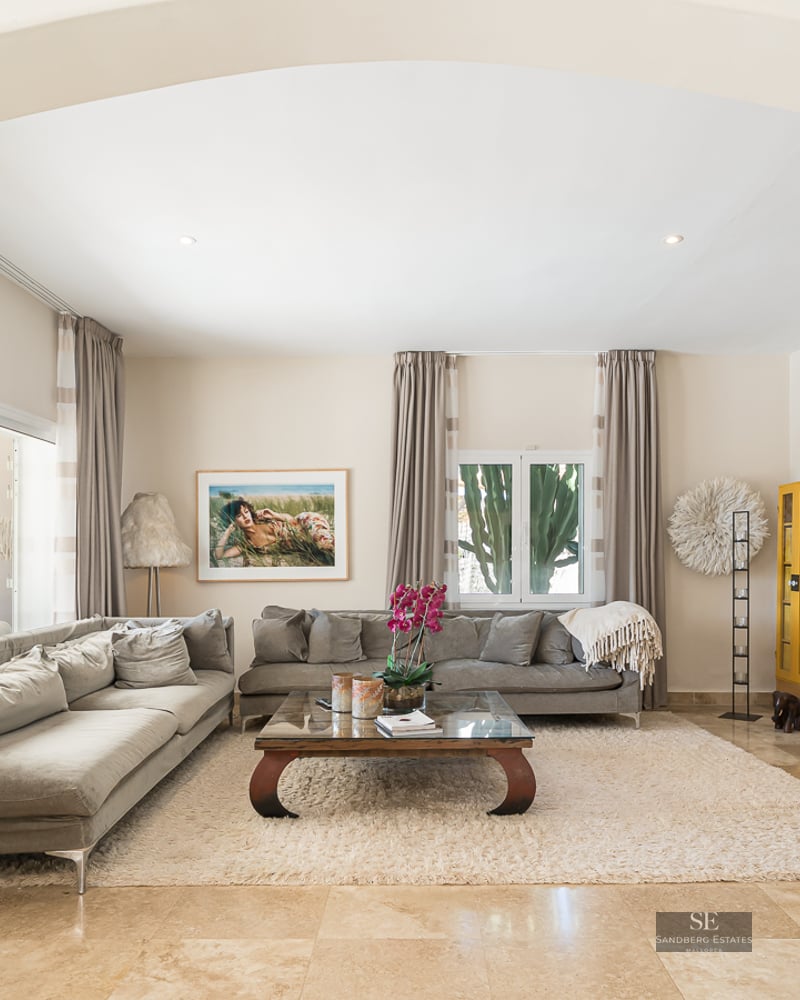 Spacious living room featuring grey sofas, a beige rug, and a large natural stone fireplace wall.