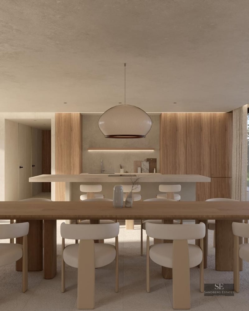 Minimalist dining area with a large wooden table, white chairs, and floor-to-ceiling windows facing a garden.