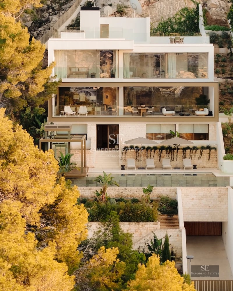 View of a modern villa featuring an infinity pool, manicured gardens, and minimalist architecture. Warm lighting and elegant outdoor furniture.