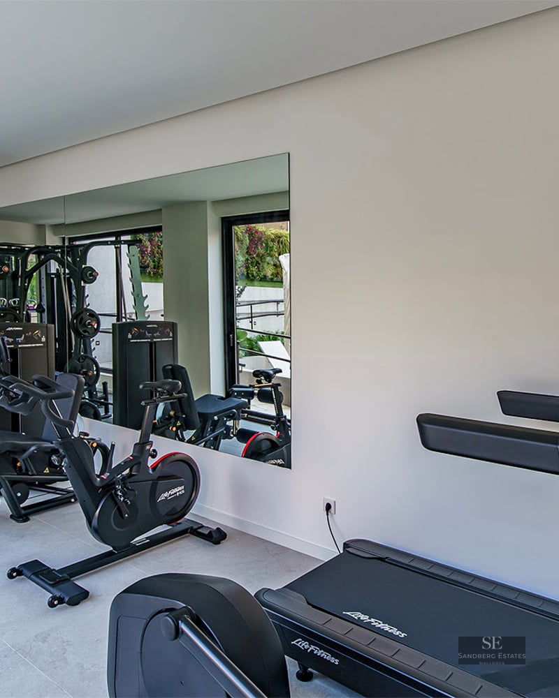 Modern indoor gym with LifeFitness treadmills, a stationary bike, and a multi-gym weight machine.