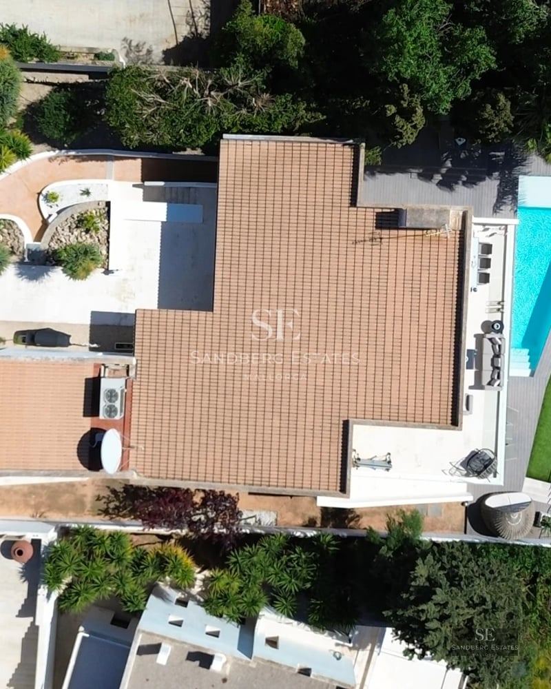 Exterior view of a modern villa featuring an infinity pool, garden, and spacious terraces. Minimalist architecture with large windows.