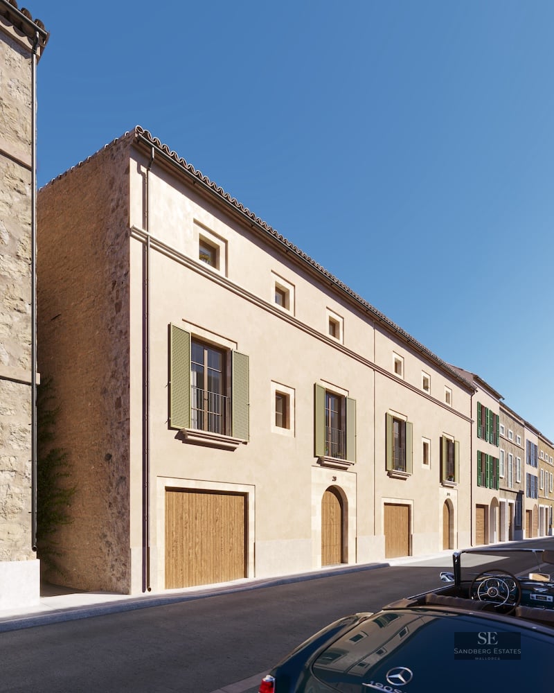 Facade of a beige Mediterranean building with green shutters, wooden doors, and a classic car on the street.
