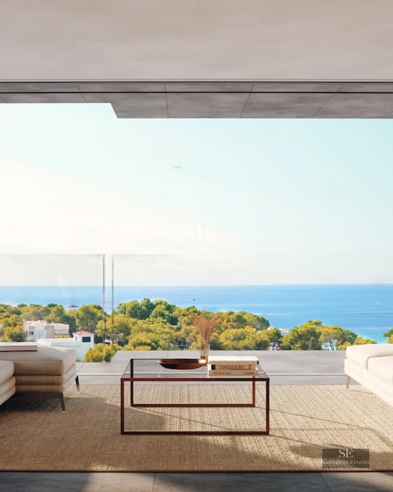 Modern interior with spacious living room and sea view. Large windows, warm lighting, and elegant designer furniture.