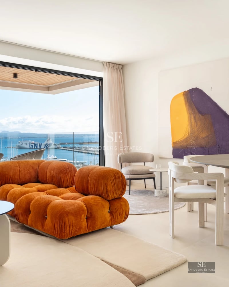 Spacious living room featuring large windows, ocean views, modern furniture, a fireplace and terrace access. Minimalist and elegant design.