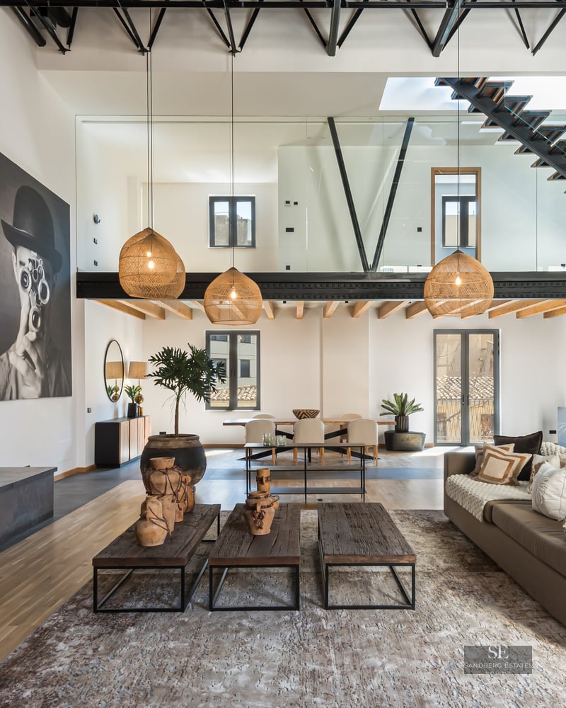 Spacious modern living room with a steel fireplace, high ceilings, floating staircase, and designer decor.