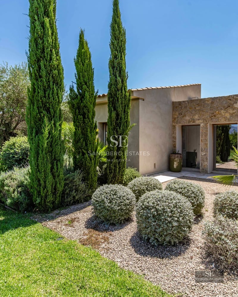 Aerial view of a luxurious house featuring an infinity pool, lush garden, and modern architecture with expansive windows.