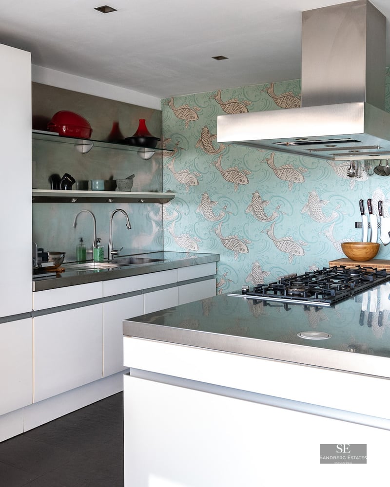 Contemporary kitchen with white cabinets, stainless steel countertops, and a unique blue koi fish wallpaper.