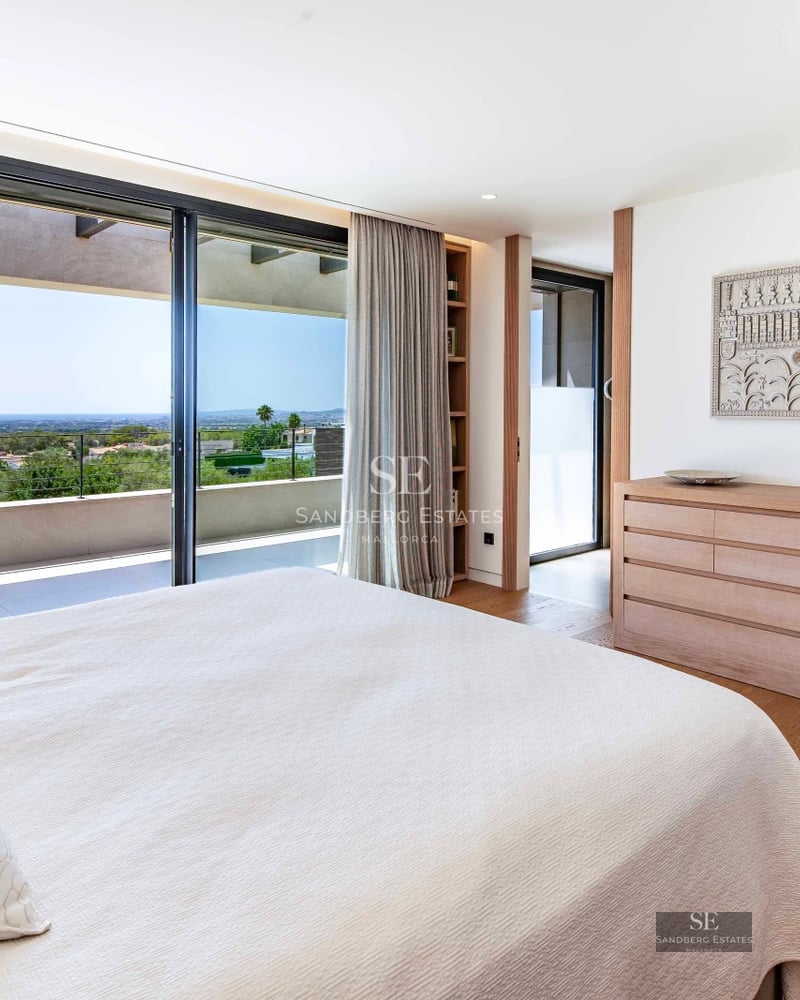 Spacious living room with floor-to-ceiling windows, modern sofas, designer rug and fireplace. View of garden with pool. Abundant natural light.