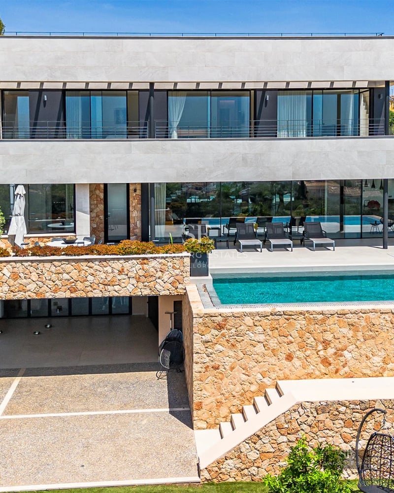 Exterior of modern house with infinity pool, lush garden, and minimalist architecture. Large windows and sunny terrace.