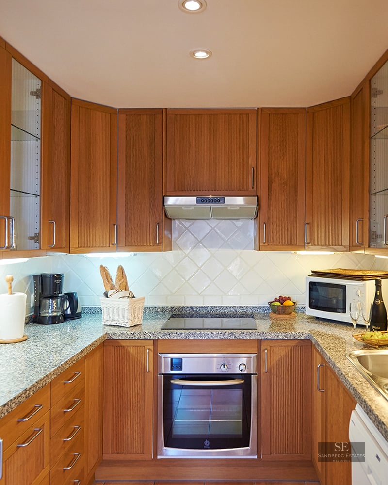 Classic U-shaped kitchen featuring wood cabinets, grey granite countertops, and integrated stainless steel appliances.