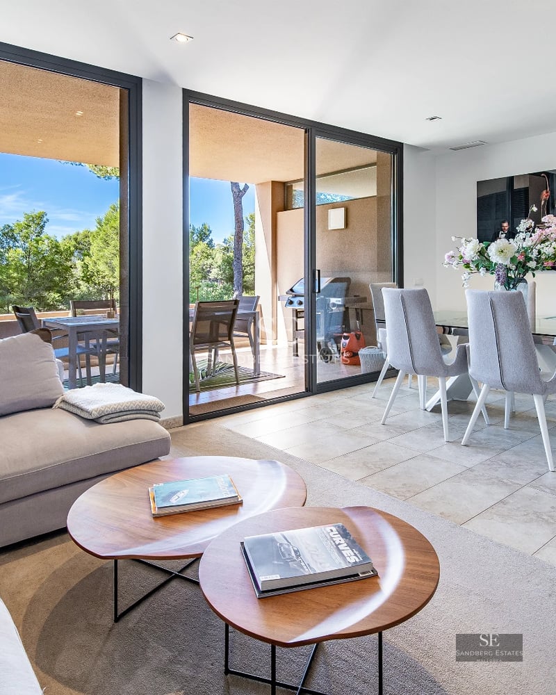 View of a modern villa featuring an infinity pool, lounge chairs, and lush greenery. Minimalist architecture and landscaping.
