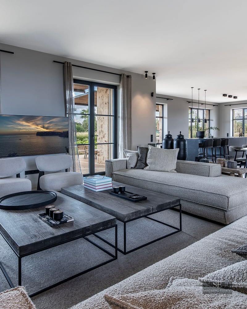 Spacious modern living room with grey sofas, wooden coffee tables, and dining area looking out to a garden.