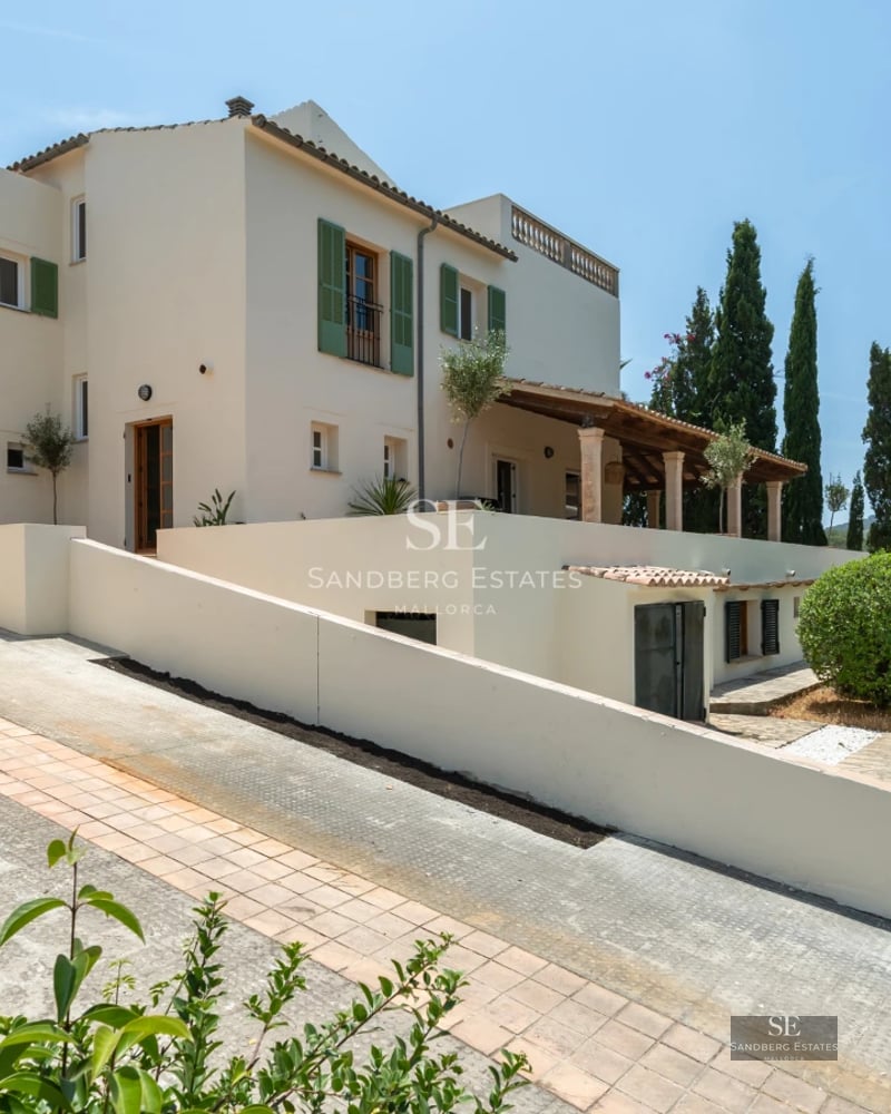 View of a modern pool with stylish loungers, surrounded by a green garden and a two-story minimalist house.