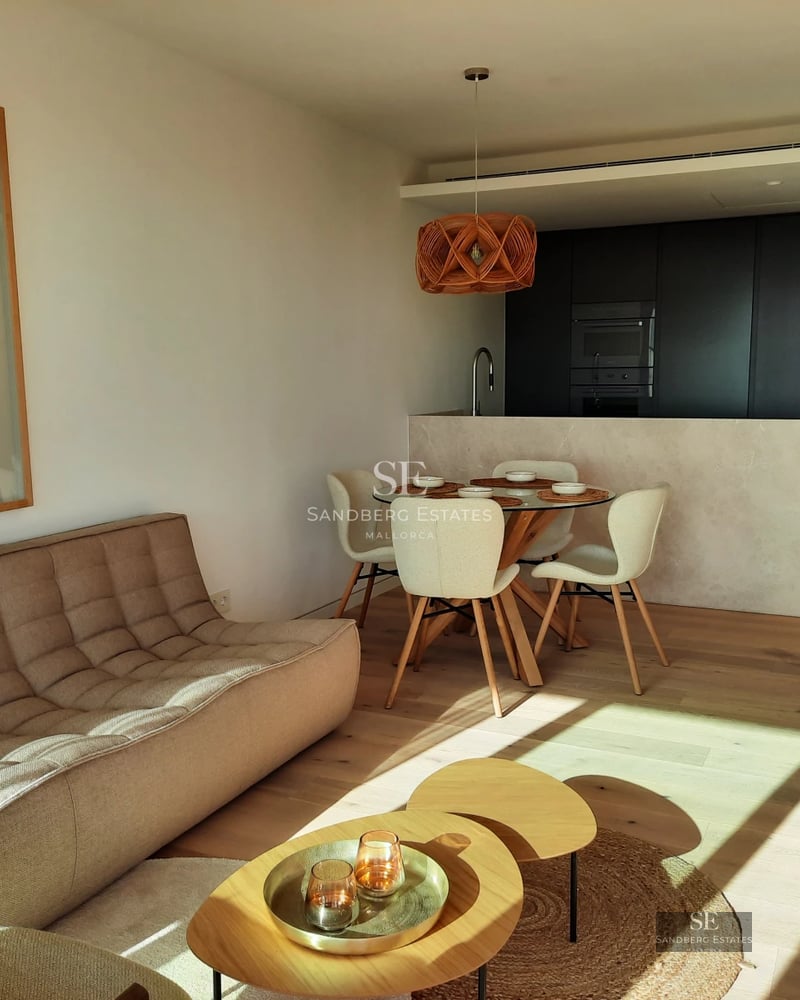 View of a blue infinity pool with white sun loungers, surrounded by greenery. Modern and elegant design.